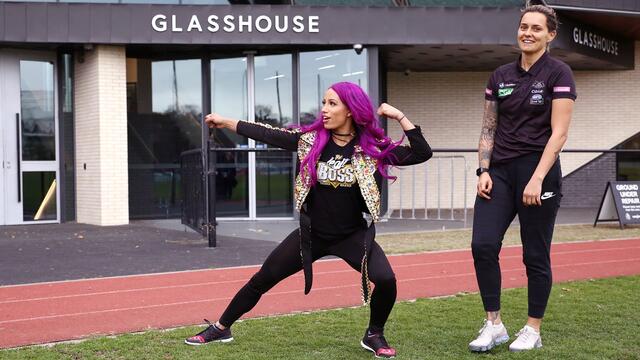 Sasha Banks kicks back with AFLW's Moana Hope background