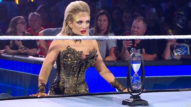 Scarlett places an hourglass in front of Roman Reigns