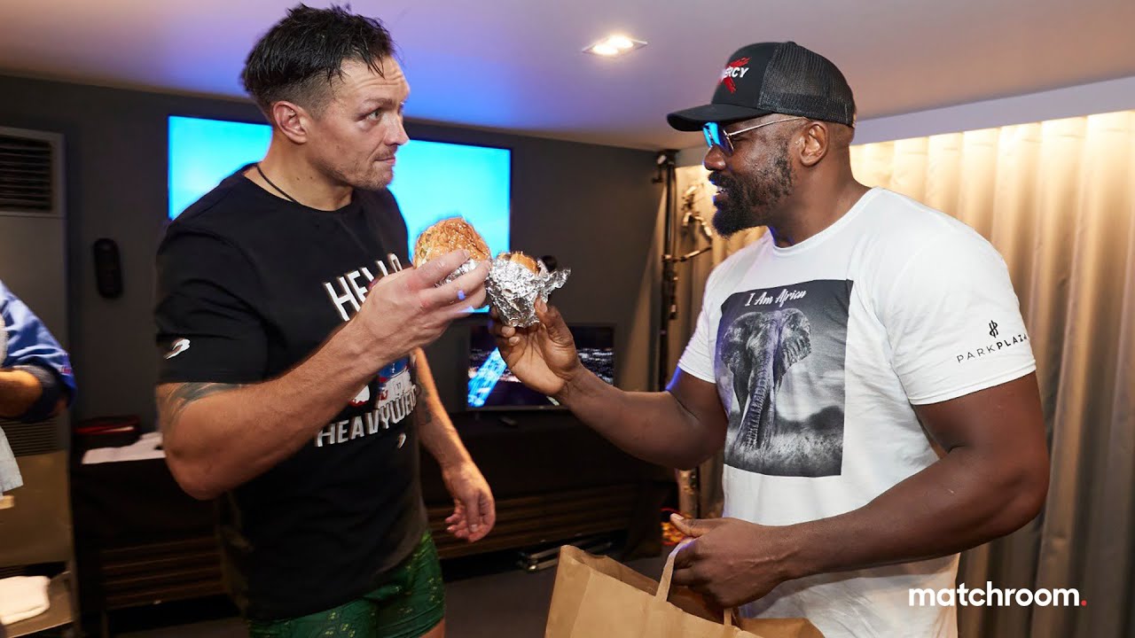Oleksandr Usyk & Derek Chisora embrace over a burger backstage background